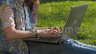 一个带着笔记本电脑的十几岁女孩。 公园里的女孩在用笔记本电脑工作。 手拿手镯